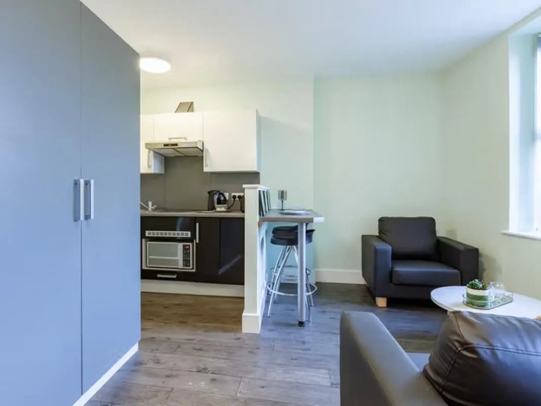 Kitchen bar stools sink microwave and armchair living room at Ty Ni in Bangor Student Accommodation