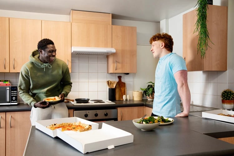 Two men eating pizza in a student kitchen at Liberty Park in Leicester Student Accommodation