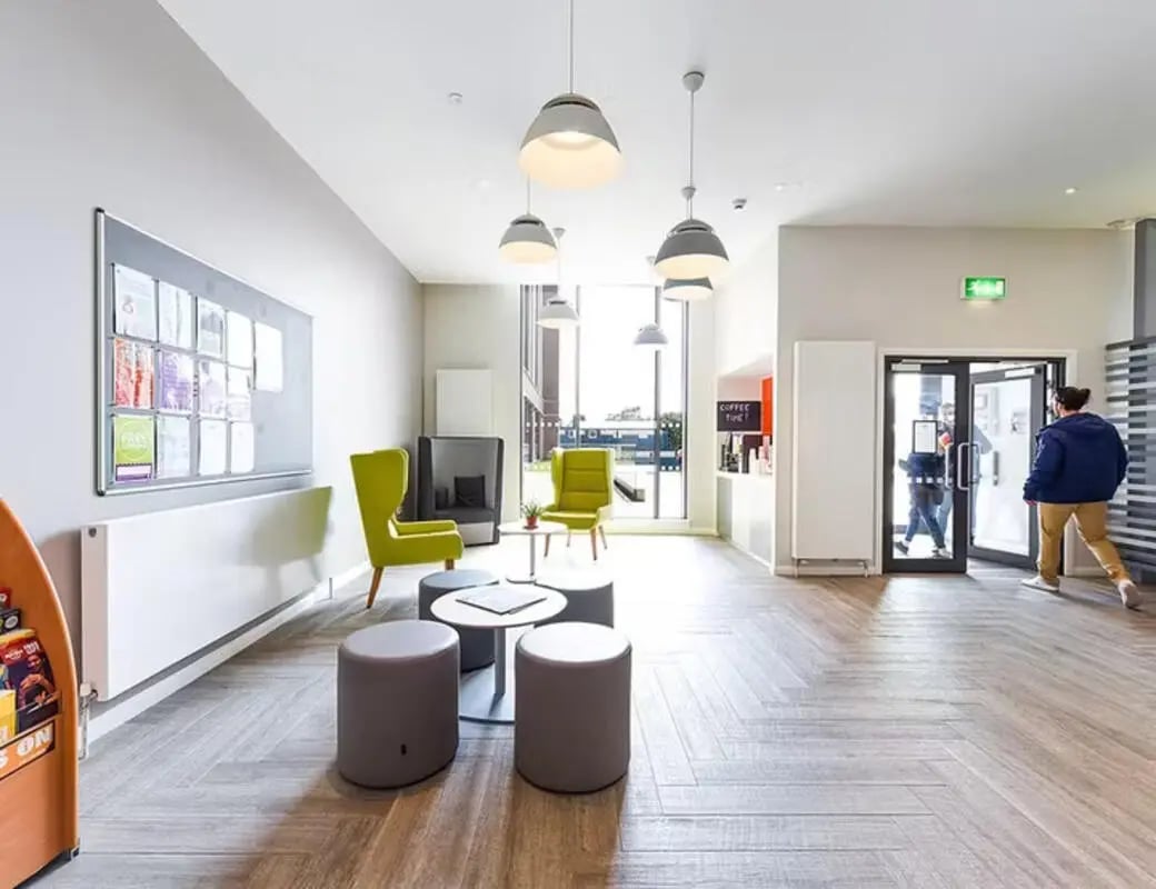 Green chairs bulletin board coffee counter common area at Merchant Studios in Glasgow Student Accommodation