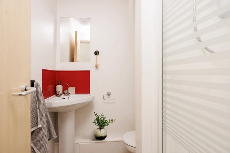 Sink mirror red backsplash towel and shower curtain bathroom at Atlantic Point in Liverpool Student Accommodation