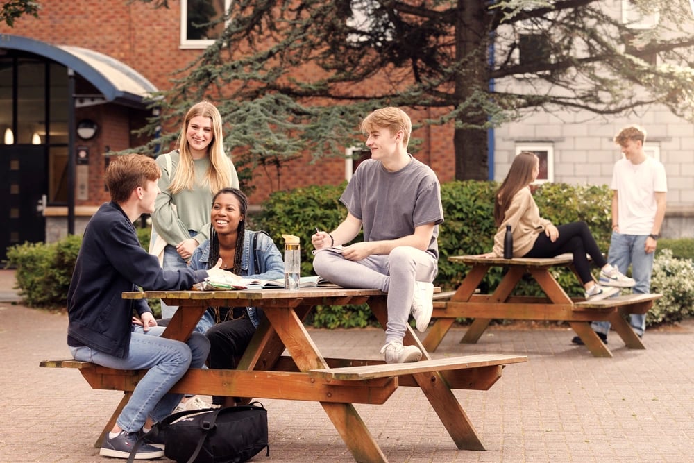 Students chatting at picnic tables outdoor seating area at Atlantic Point in Liverpool Student Accommodation