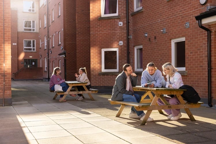 Students sitting at picnic tables exterior common area at Moorfield in Liverpool Student Accommodation