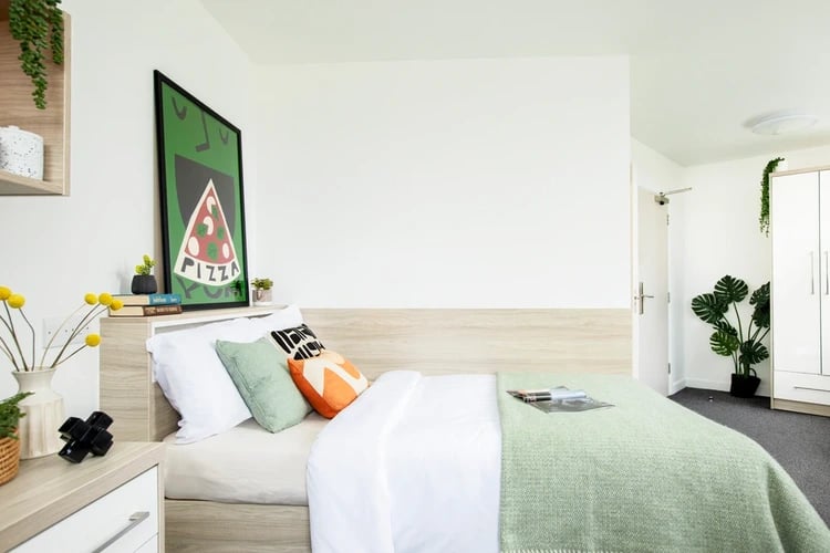 Bed with pizza art and green blanket bedroom at Arbour House in London Student Accommodation