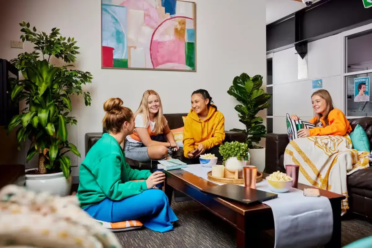 Students relaxing on couch with snacks living room at Mountain x Scape in Sydney Student Accommodation