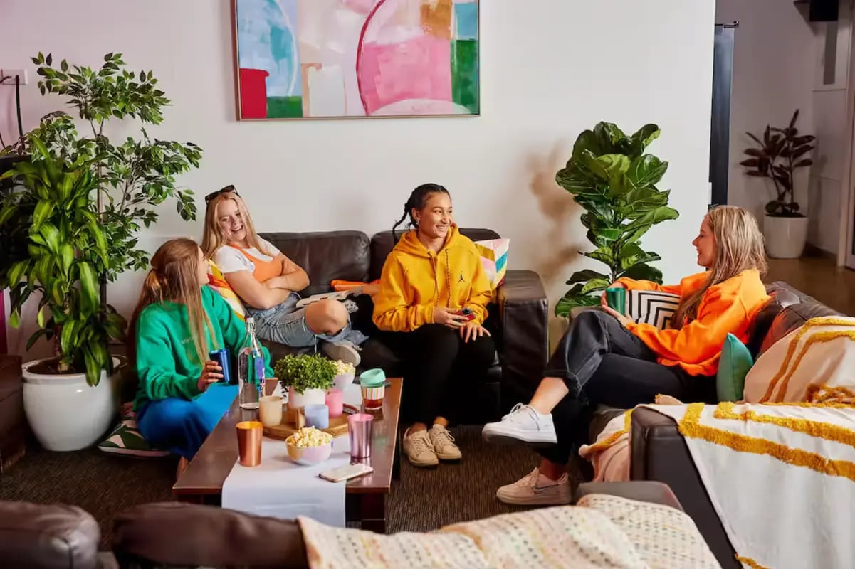 Four students chat and relax on sofas Living room at Mountain x Scape in Sydney Student Accommodation