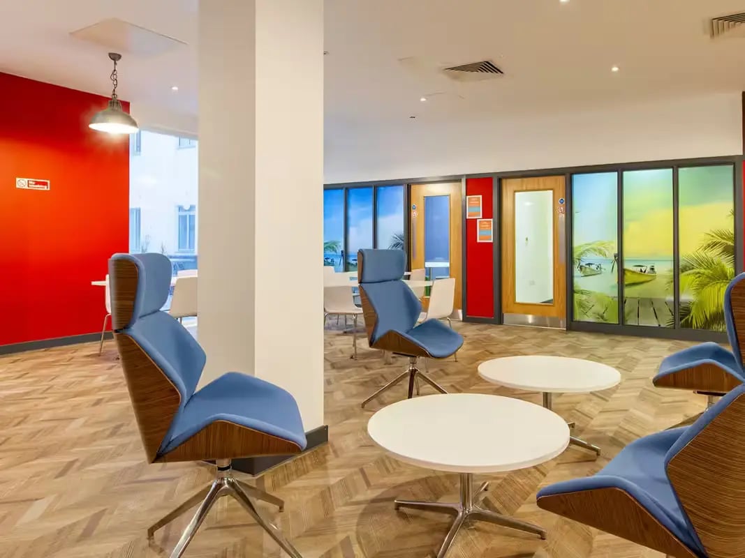 Blue chairs white tables wooden floor lounge area at Plymouth Cross House in Plymouth Student Accommodation