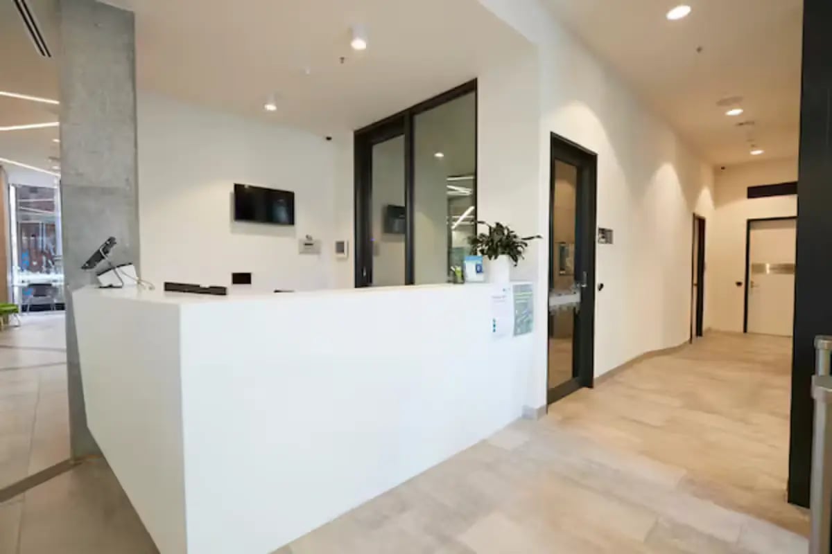 White reception desk with monitor and plants reception area at Scape Berkeley 2 in Melbourne Student Accommodation