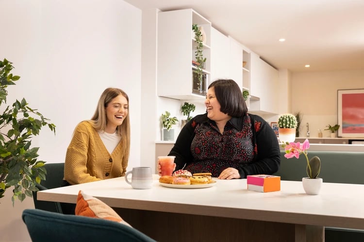 Two women dining area with snacks and drinks Kitchen at Bromley Place in Nottingham Student Accommodation