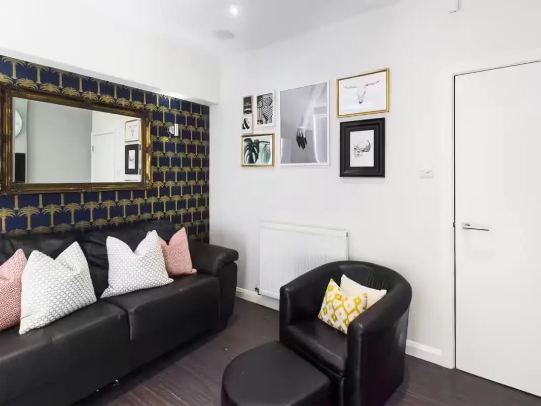 Black leather sofa armchair ottoman gallery wall living room at 41 Guildford Street in Stoke-On-Trent Student Accommodation