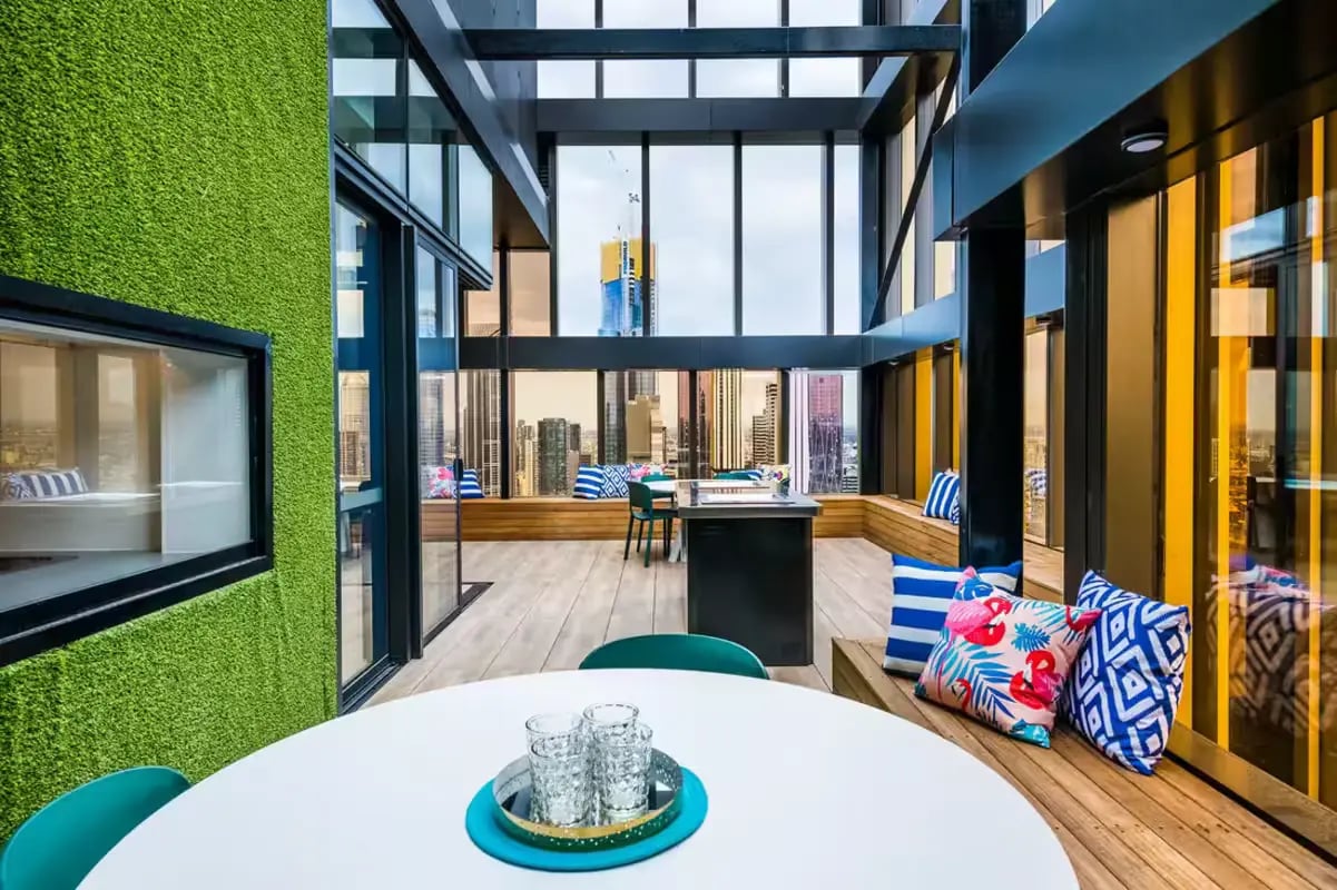 White table green chairs city view living area at Scape La Trobe in Melbourne Student Accommodation