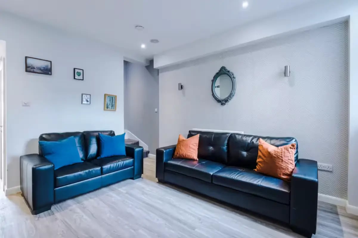Black sofas with blue orange cushions mirror living room at 32 Cauldon Road in Stoke-On-Trent Student Accommodation
