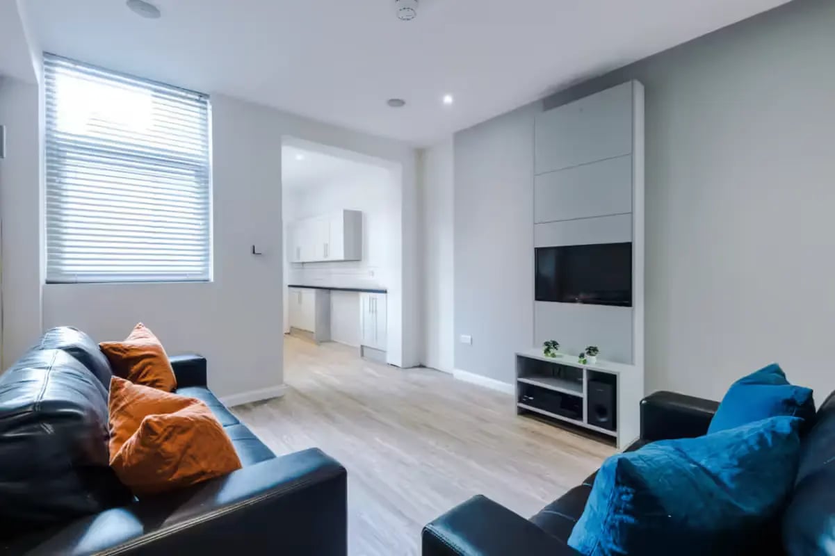 Black sofas with orange blue pillows living room at 32 Cauldon Road in Stoke-On-Trent Student Accommodation