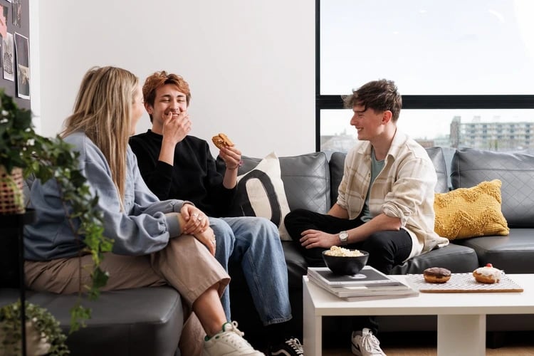 Students relax on sofa with snacks living room at Chaucer House in Portsmouth Student Accommodation
