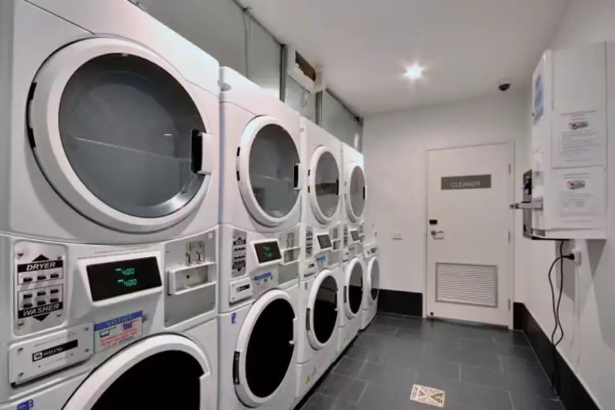 Stacked dryers washers on tiled floor laundry room at Scape Berkeley in Melbourne Student Accommodation