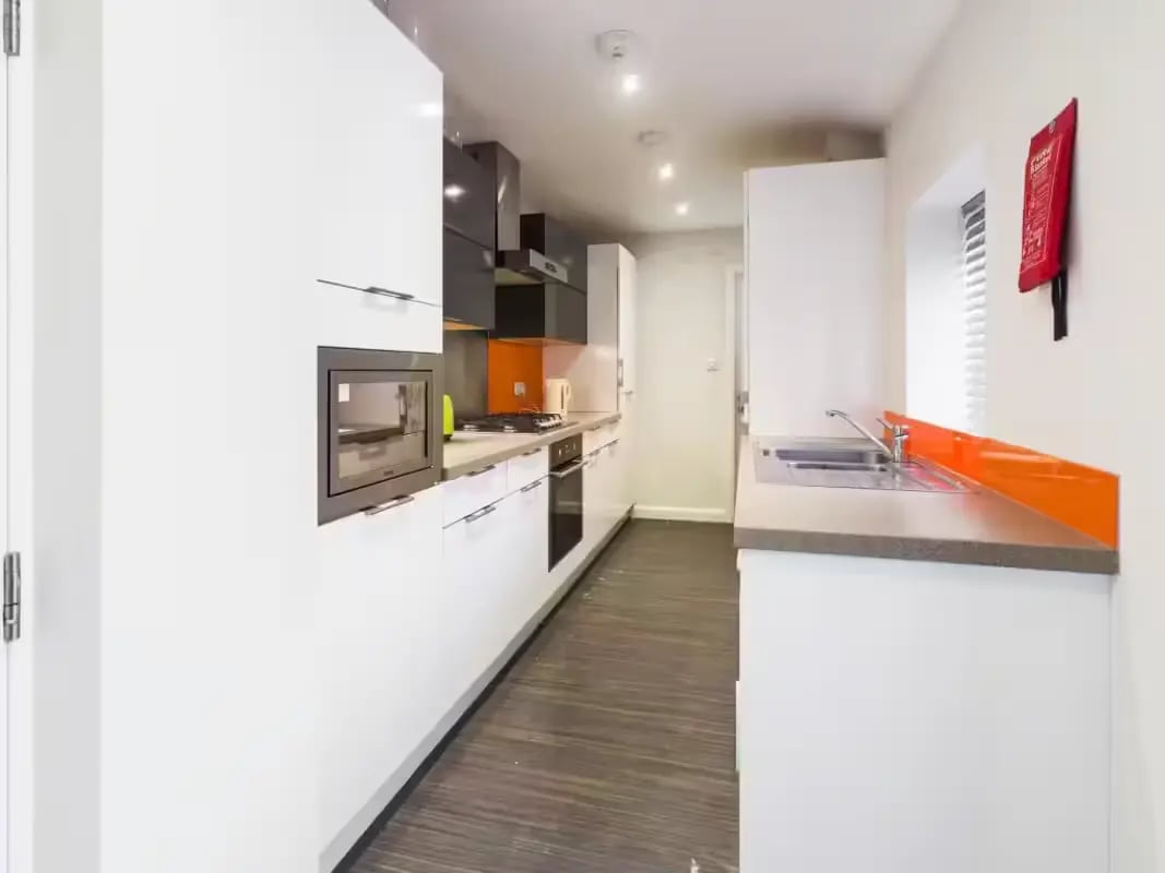 Modern white kitchen with orange backsplash sink kitchen at 125 Leek Road in Stoke-On-Trent Student Accommodation