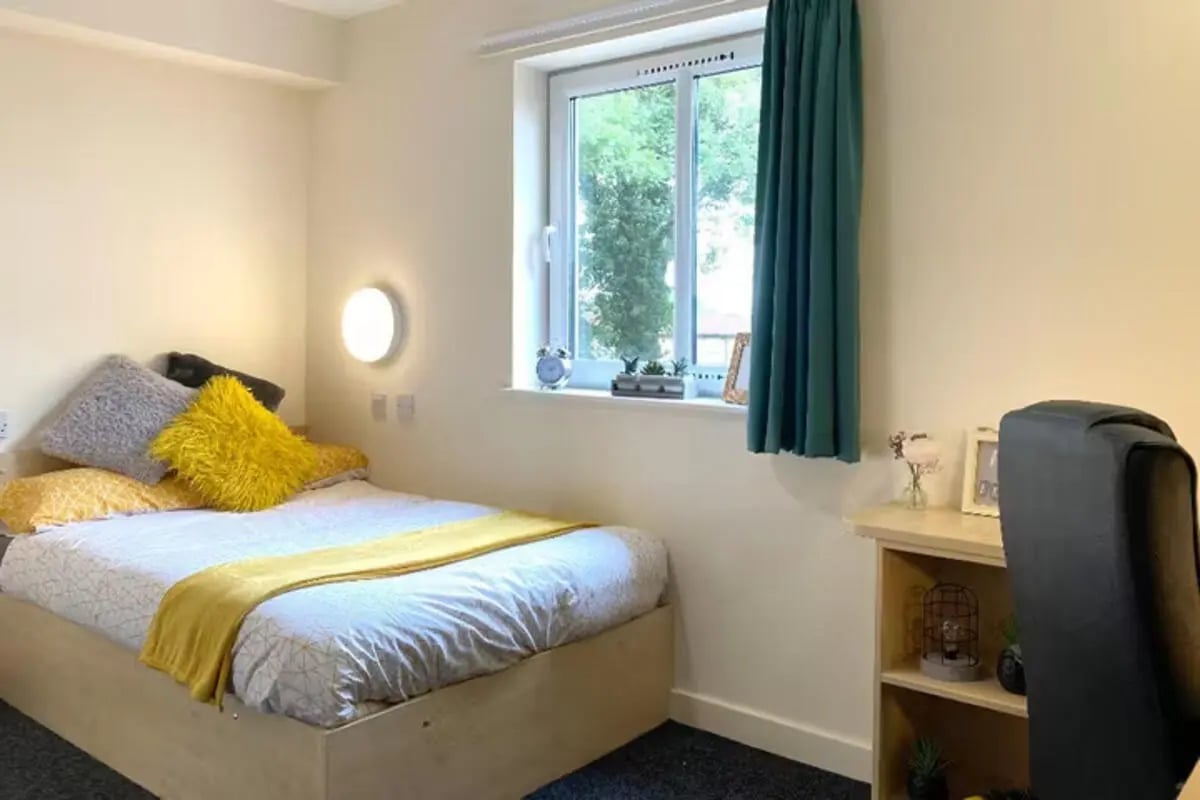 Bed with colorful pillows yellow throw near window bedroom at The Cube - Loughborough in Loughborough Student Accommodation