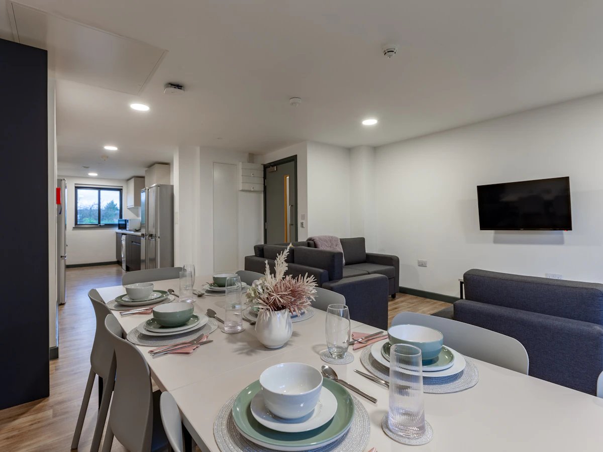 Dining table set with place settings and seating living room at Red Queen - Coventry in Coventry Student Accommodation