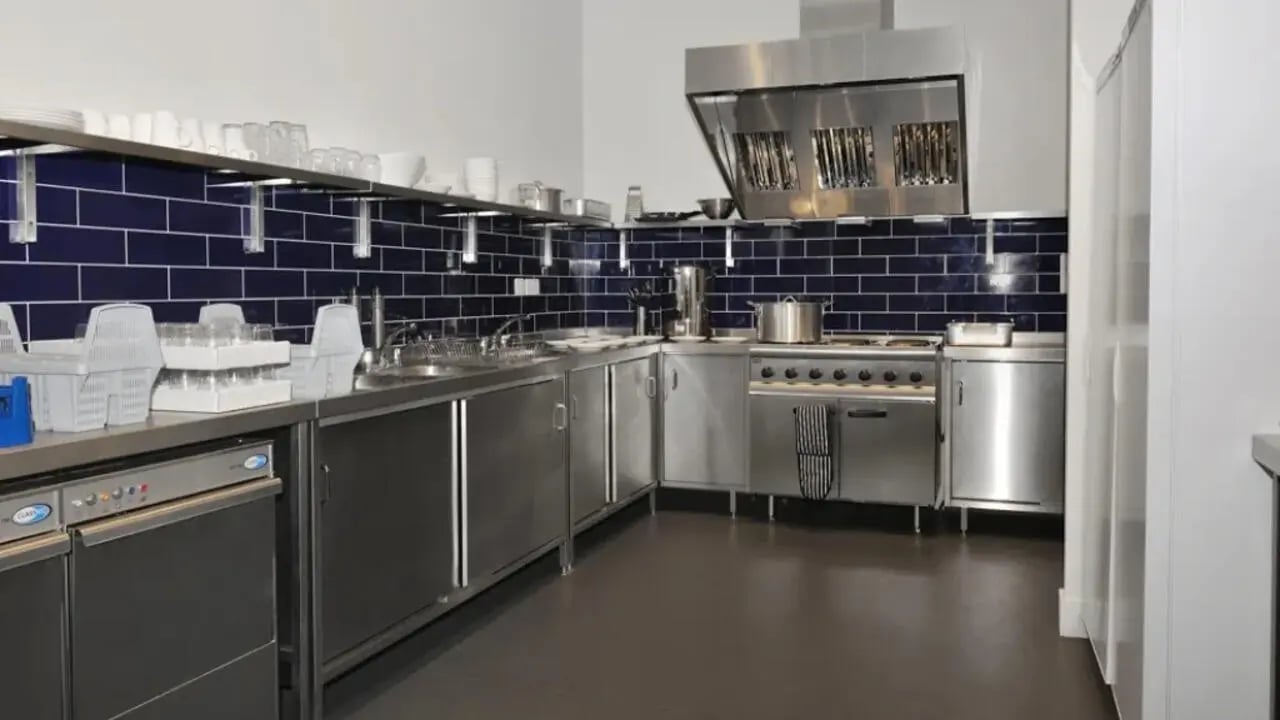 Commercial stainless steel kitchen with dark blue tile kitchen at Victoria Hall Kings Cross in London Student Accommodation