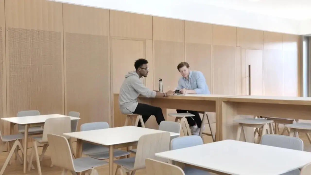 Two students at large table with chairs common area at Victoria Hall Kings Cross in London Student Accommodation