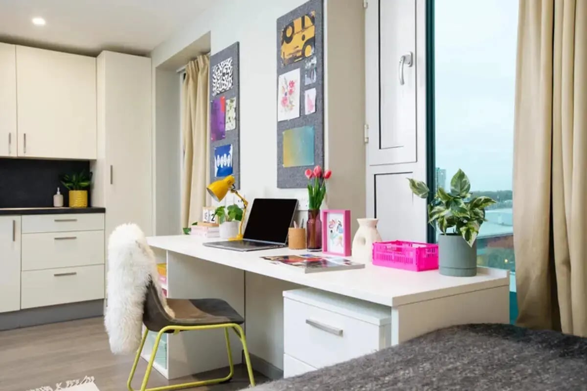 Desk with laptop and kitchen area Bedroom at Stapleton House in London Student Accommodation