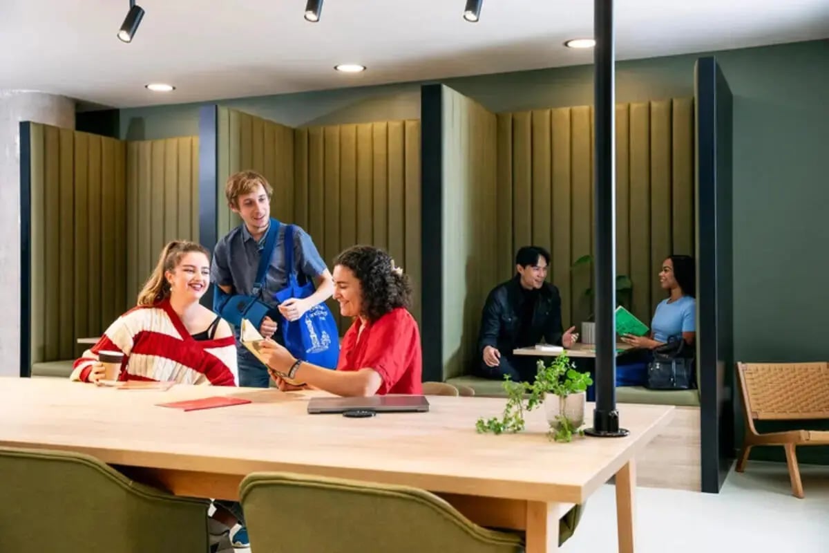 Students talking at study tables in booths communal area at Stapleton House in London Student Accommodation
