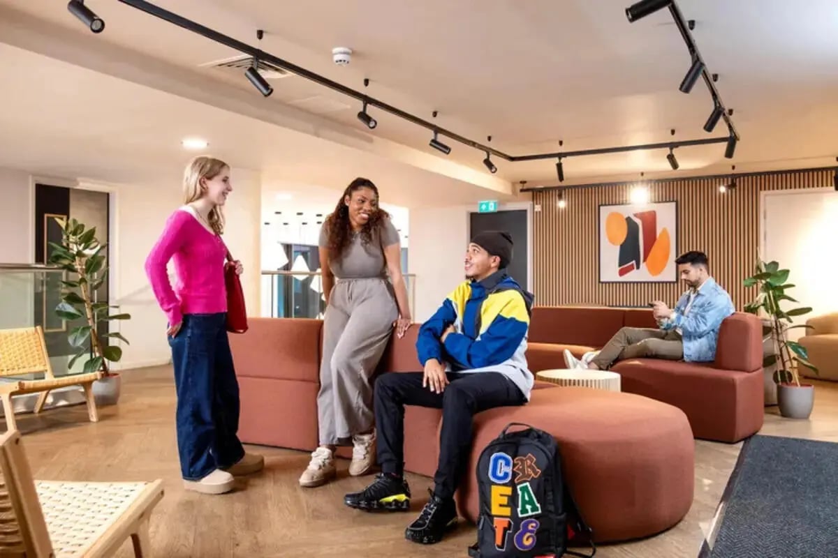 Students talking on sectional sofa modern living room at Stapleton House in London Student Accommodation