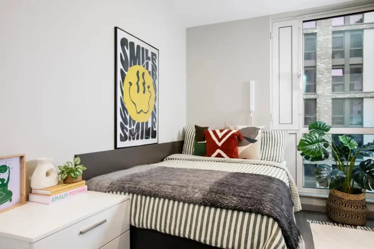 Bed with pillows poster and plants bedroom at Stapleton House in London Student Accommodation