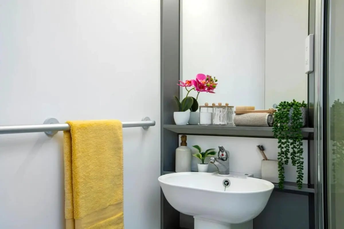 Sink towels orchid plants cotton swabs bathroom at Quantum Court in London Student Accommodation