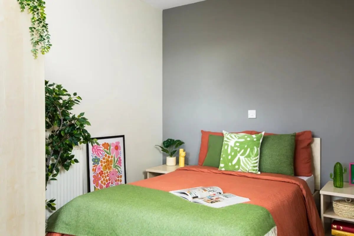 Bed with plants and colorful artwork bedroom at Quantum Court in London Student Accommodation