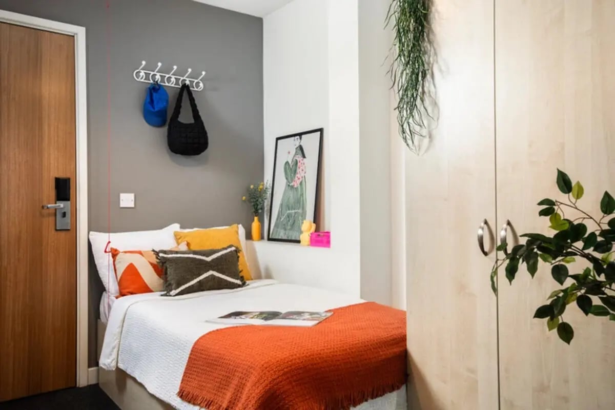 Bed with orange blanket and pillows bedroom at Quantum Court in London Student Accommodation