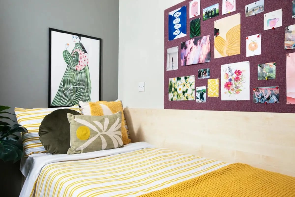 Yellow striped bed artwork and photos bedroom at Quantum Court in London Student Accommodation