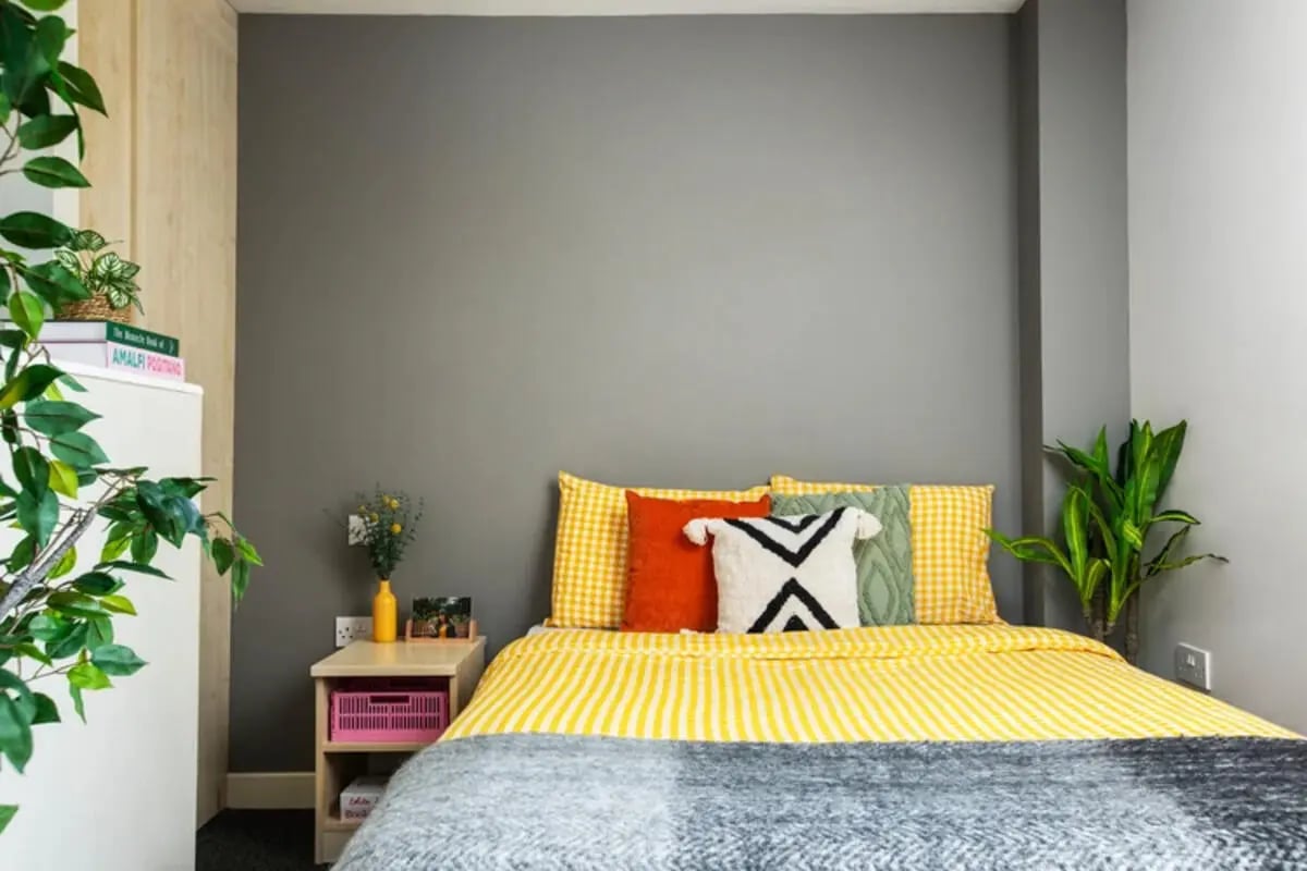 Yellow striped bed with decorative pillows bedroom at Quantum Court in London Student Accommodation