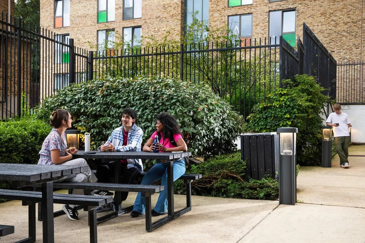 Students sitting at picnic tables exterior area at Quantum Court in London Student Accommodation
