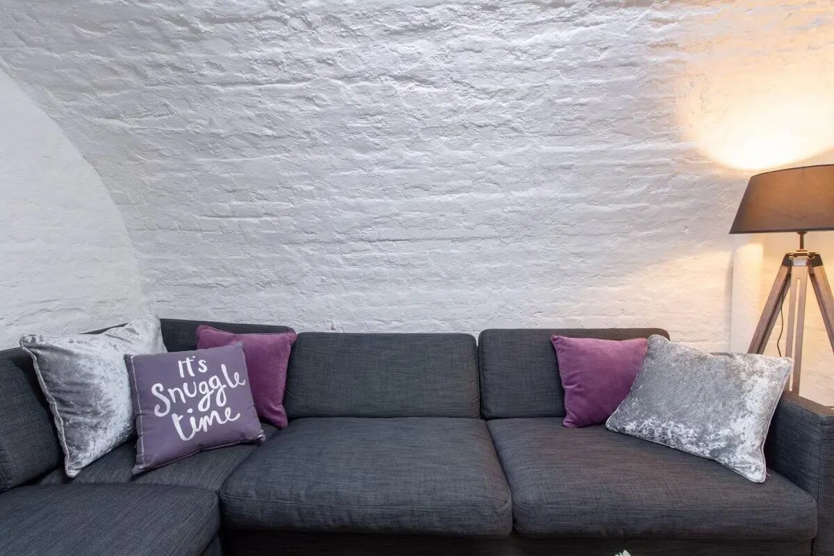 Gray sofa with purple and silver throw pillows living room at Bloomsbury Janet Poole House in London Student Accommodation