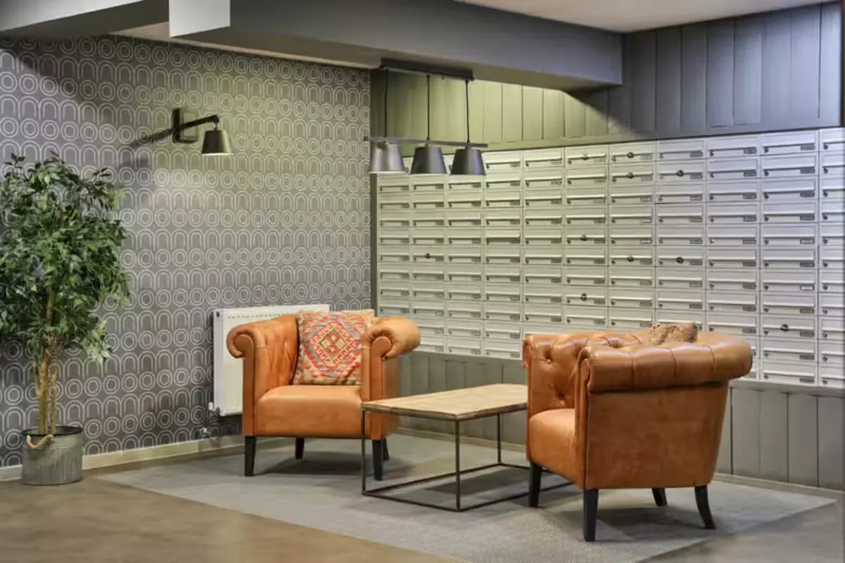 Two armchairs coffee table mailboxes living area at The Frontage in Nottingham Student Accommodation