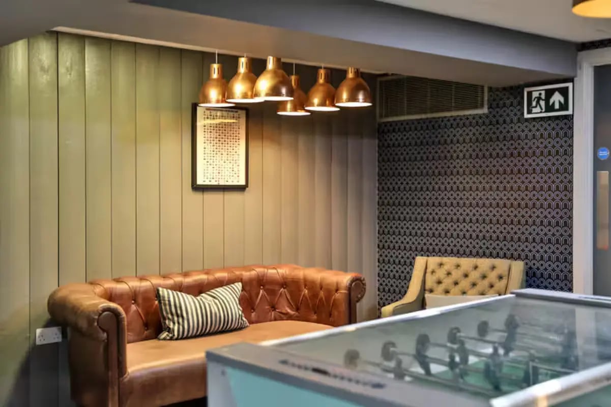 Brown tufted couch foosball table common area at The Frontage in Nottingham Student Accommodation