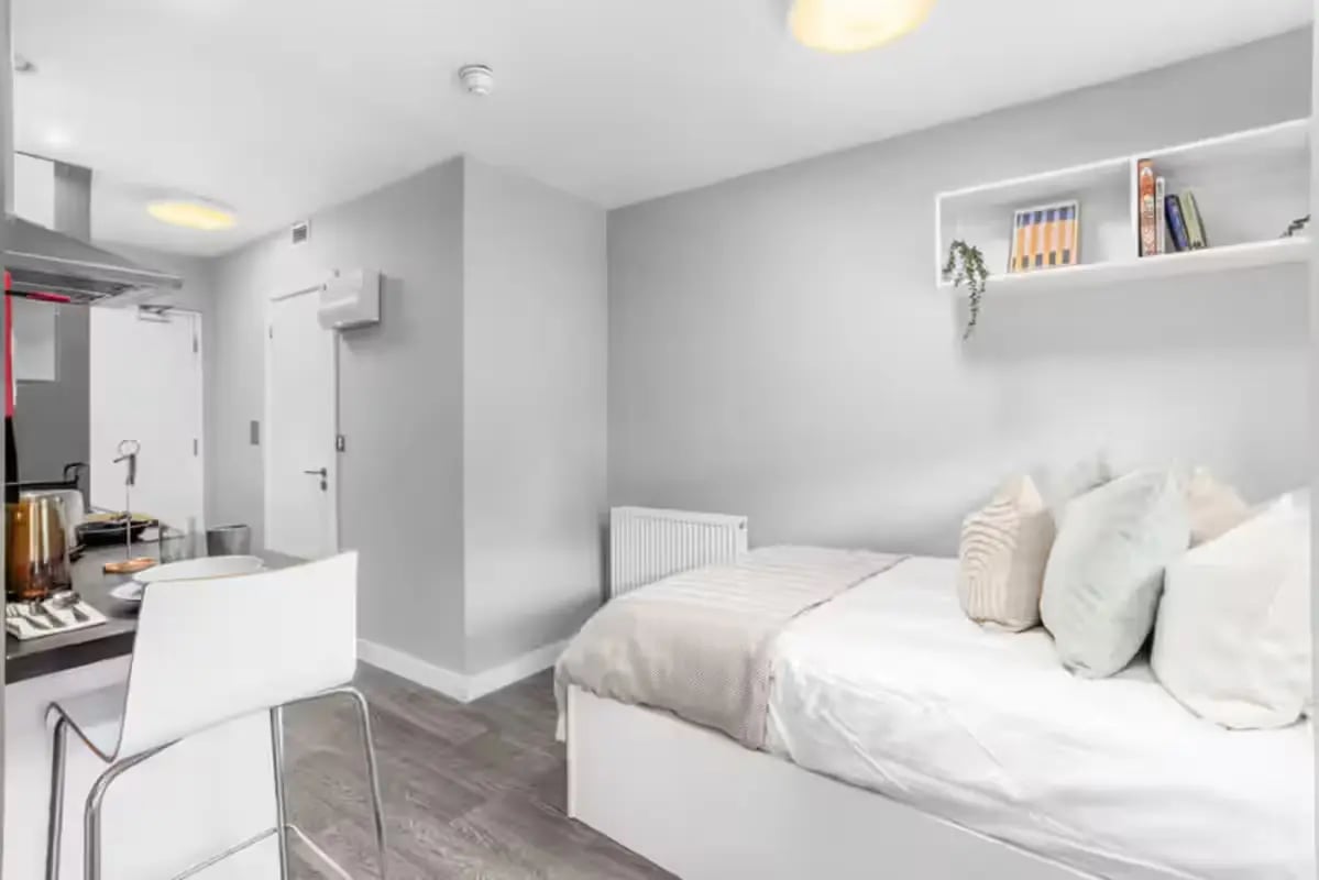 Bed with pillows and kitchenette study area living room at Northgate House Apartments in Cardiff Student Accommodation