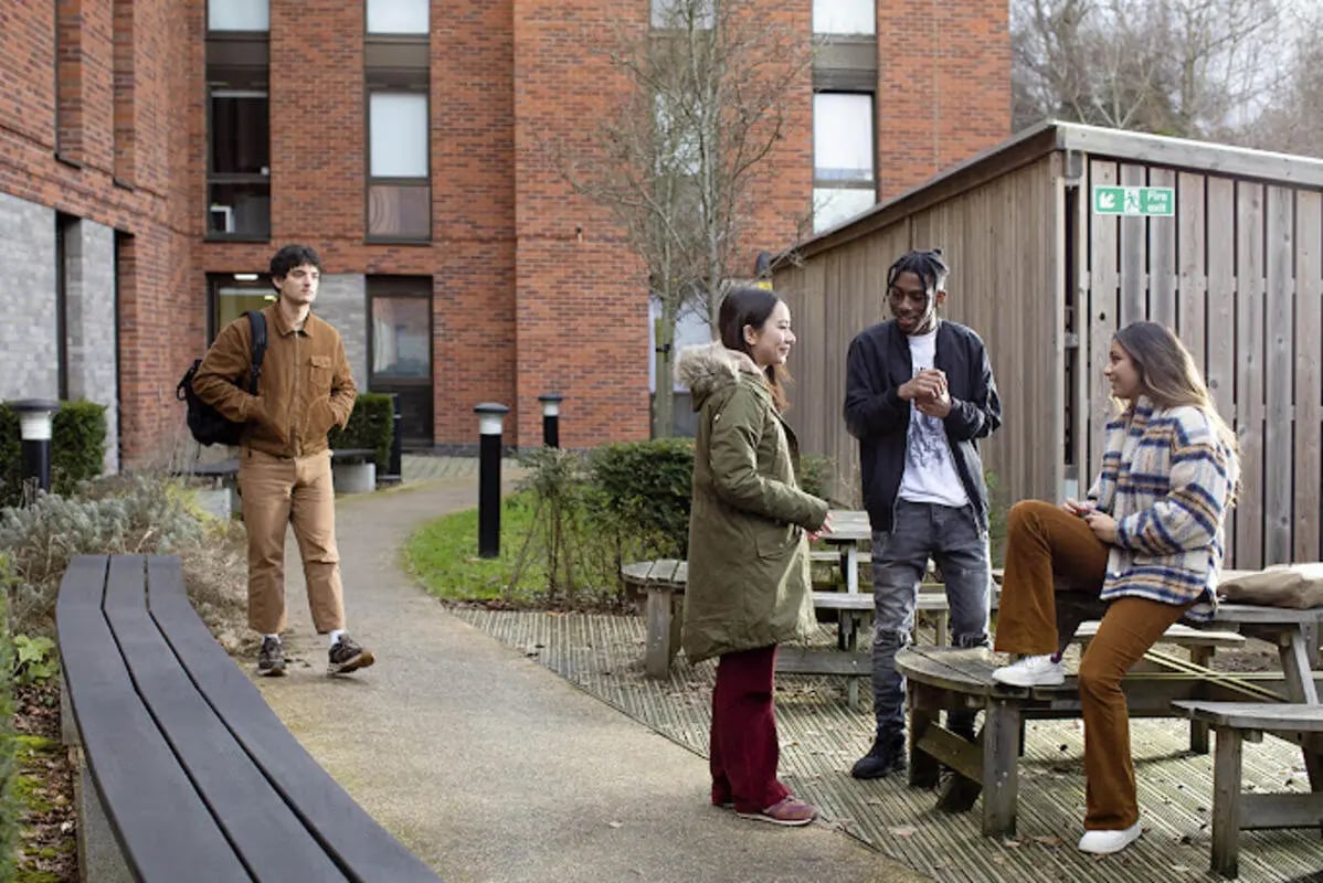 Students outside building on picnic tables exterior at Athena Studios in Birmingham Student Accommodation