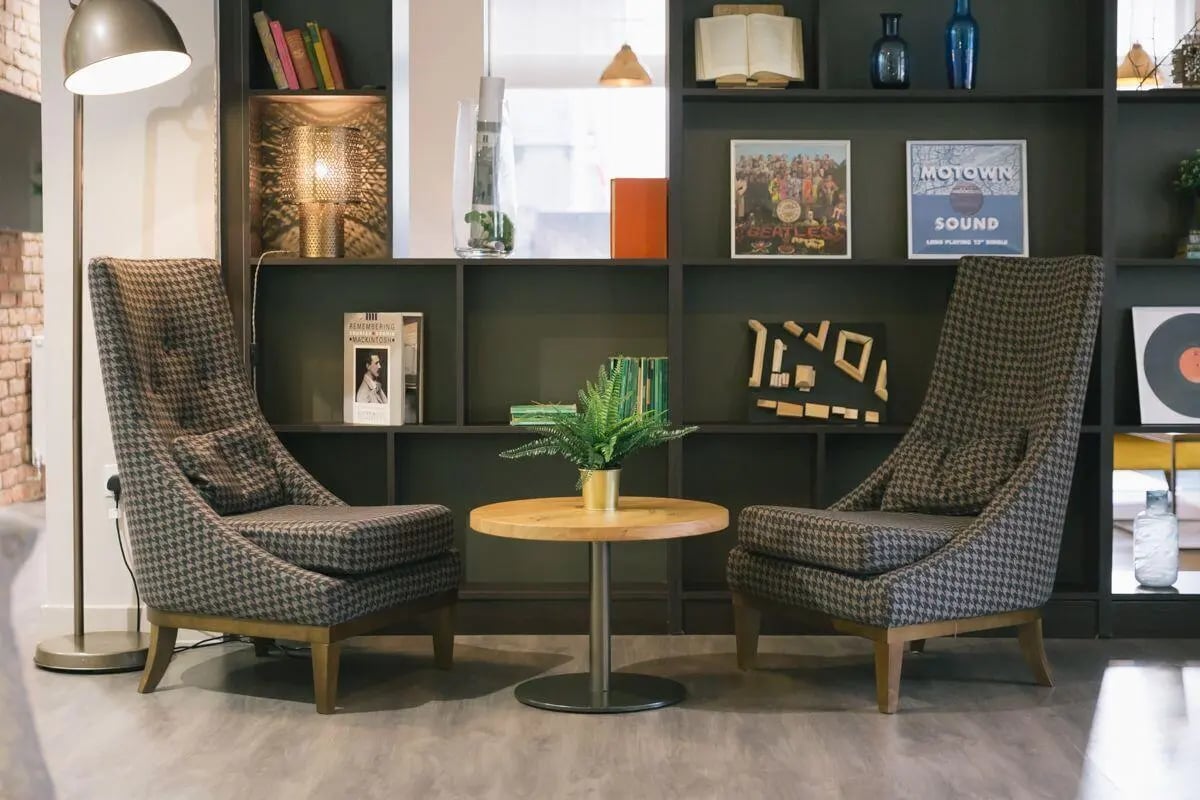 Two patterned chairs small round table bookshelves living room at Bath Street in Glasgow Student Accommodation