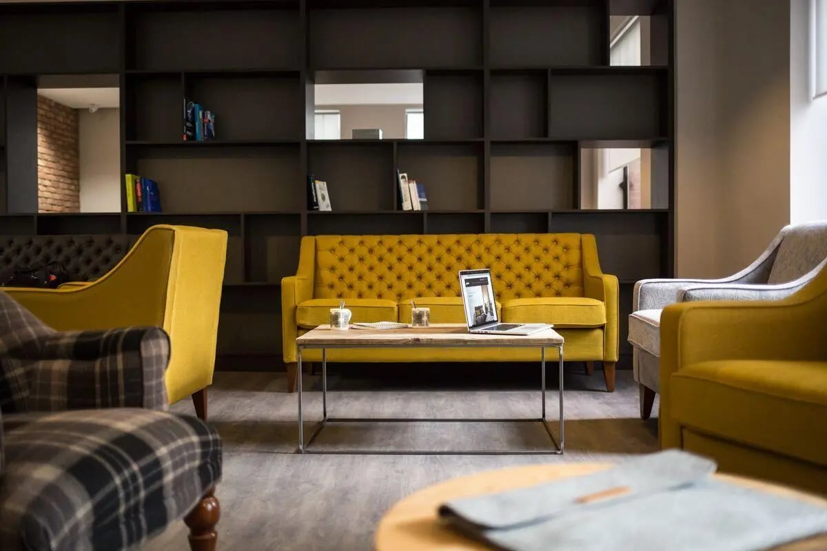 Yellow tufted sofa with laptop and cups living room at Bath Street in Glasgow Student Accommodation