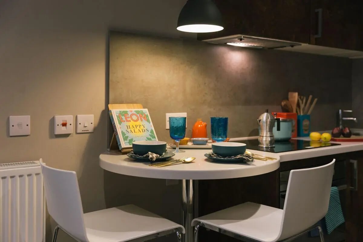 Table with chairs cook book and kitchen counter kitchen at Bath Street in Glasgow Student Accommodation