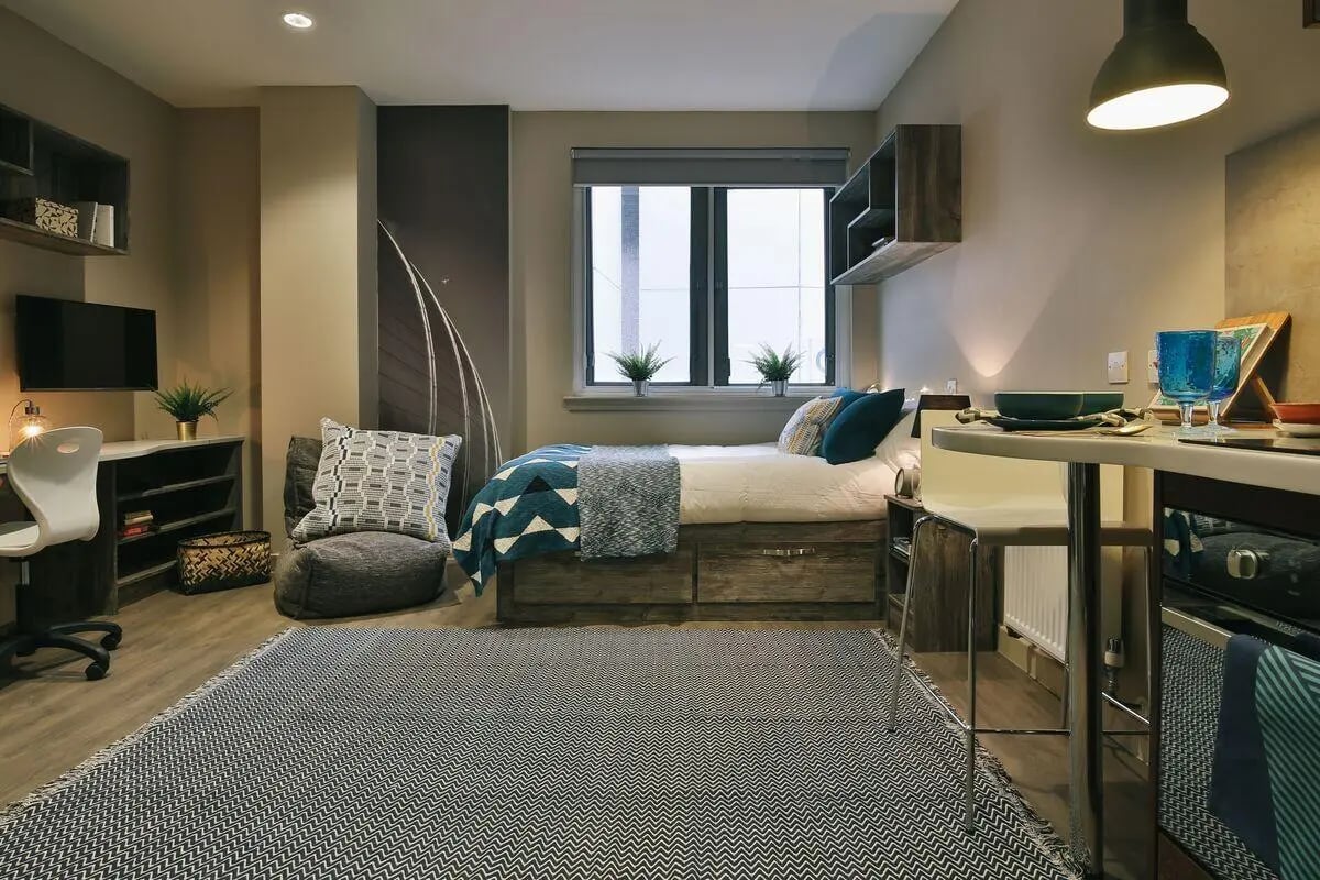 Bed desk chair rug and plants living room at Bath Street in Glasgow Student Accommodation