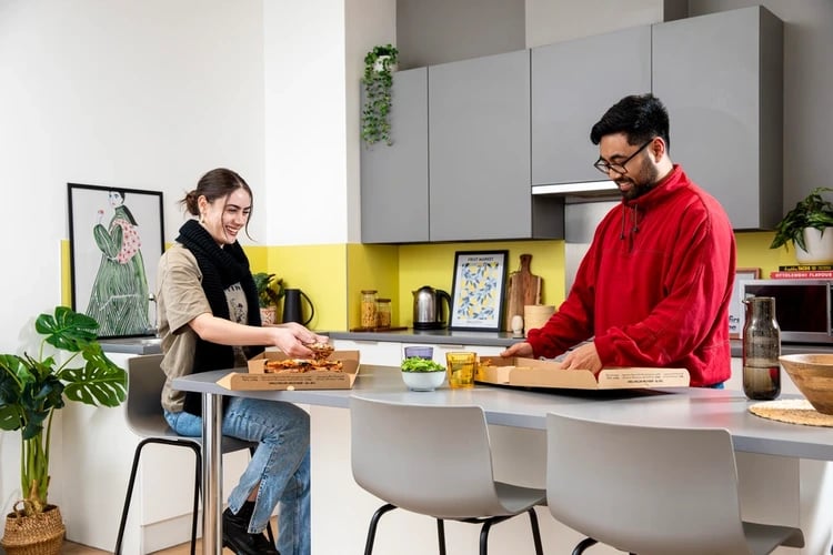 Two people with pizza kitchen island kitchen at Brunel House in Bristol Student Accommodation