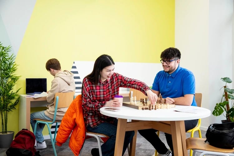Students playing chess by desk with laptop common area at Brunel House in Bristol Student Accommodation