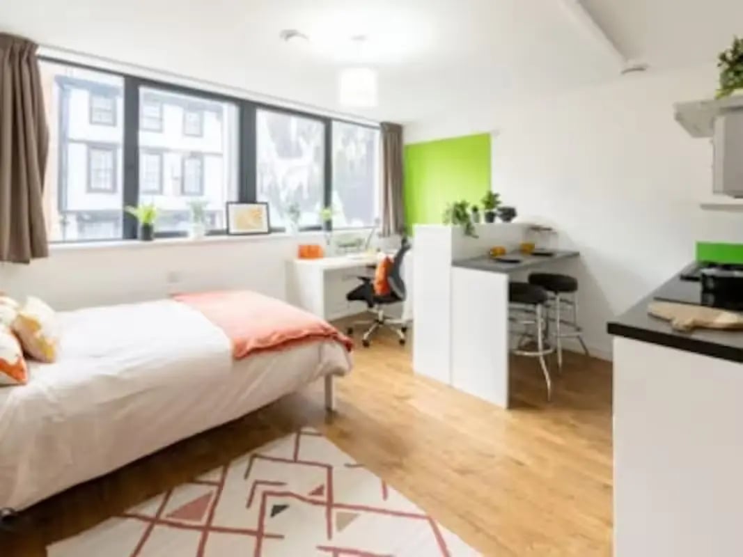 Bed desk chair bar stools and kitchen area room at St Lawrence House in Bristol Student Accommodation