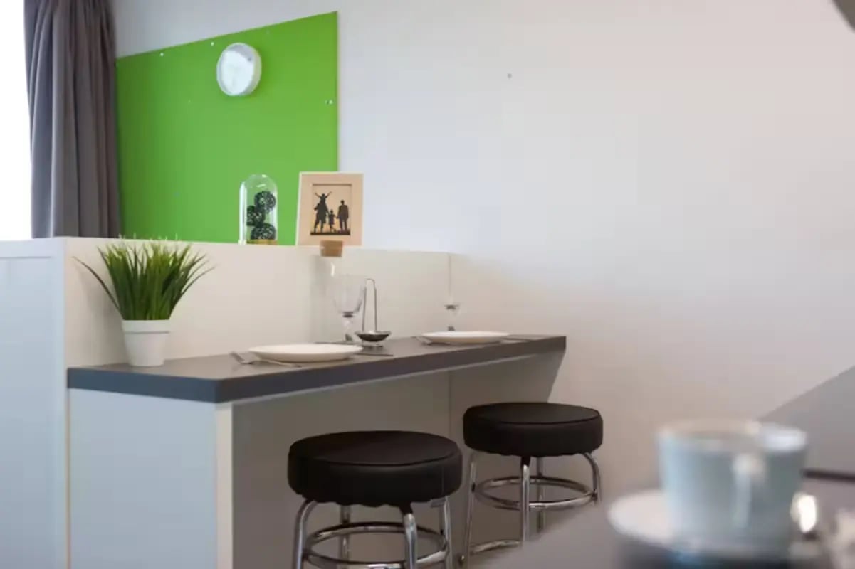Table with stools plant and clock kitchen area at St Lawrence House in Bristol Student Accommodation