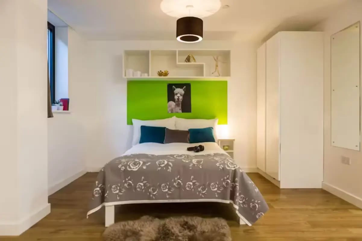 Bed with llama art green wall wardrobe bedroom at St Lawrence House in Bristol Student Accommodation