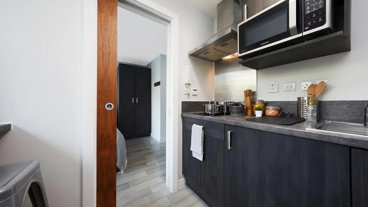 Modern kitchen with microwave and dark cabinets kitchen at Collegiate Tower in Bristol Student Accommodation
