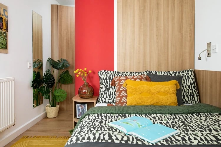 Bed with patterned bedding plant and open book Bedroom at North Lodge in London Student Accommodation
