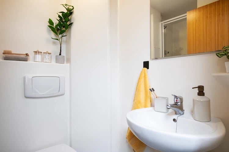 Sink with soap dispenser and yellow towel Bathroom at Pacific Court in London Student Accommodation